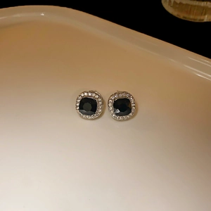 Detailed macro view of square black crystal stud earrings with a sparkling diamond halo