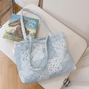 Detail of blue and white patchwork quilted tote bag with floral patterns on a chair