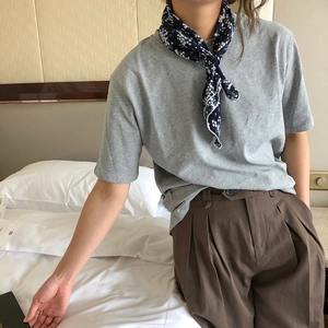 Detail of a navy patterned neck scarf styled with a grey T-shirt on a model