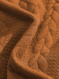 Macro shot of premium burnt orange jacquard fabric with textured diamond quilting detail