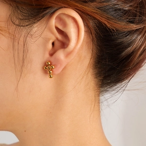 Golden beaded cross stud earrings in polished stainless steel for women on ear model