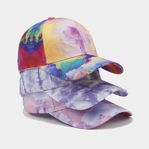 Detailed stack of three vibrant tie-dye baseball caps showing twill cotton texture