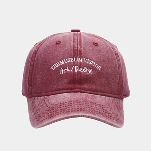 Detail of white embroidery and vintage washed texture on a burgundy cotton baseball cap