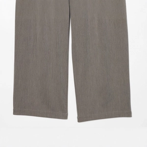 Gros plan détaillé du pantalon gris montrant la texture du tissu et la couture du bas