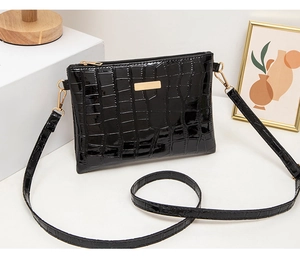 Close-up of black crocodile embossed envelope bag with polished gold-tone metal hardware
