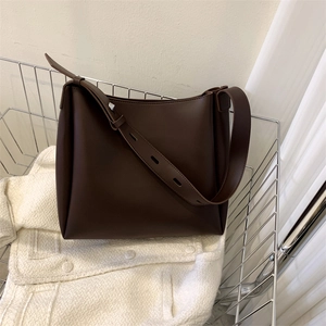 Detail of dark brown leather tote bag strap and smooth texture in a minimalist setting