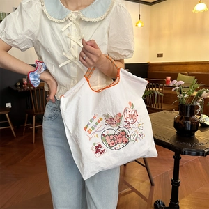 Detail der weißen Einkaufstasche mit buntem Graffiti-Print und orangen Webgriffen