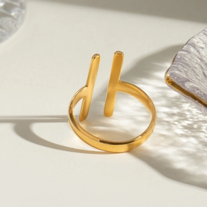 Minimalist geometric open ring in gold stainless steel on an elegant glass surface