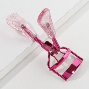 Detail of pink glitter handle eyelash curler with soft silicone pad on white background