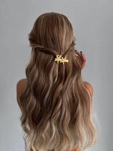 Détail de deux pinces à cheveux étoiles de mer dorées sur de longs cheveux ondulés