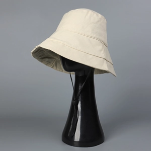 Close-up of beige wide brim bucket hat with UPF50+ coating and adjustable black wind cord
