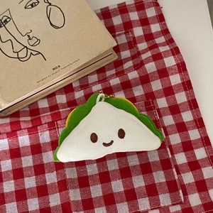 Macro view of cute plush sandwich keychain with a golden chain on a checkered background