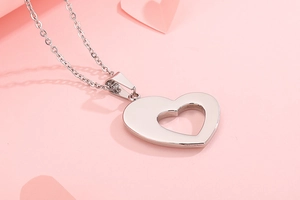 Detailed view of silver heart pendant with hollow design on romantic pink background