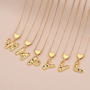 Macro view of gold alphabet heart pendants with vibrant colorful zircon stones