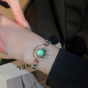 Macro shot of rose gold watch band featuring white crystals and emerald green sunray dial