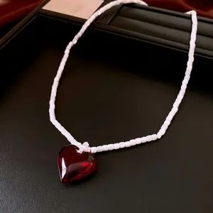 Elegant cat eye beaded necklace featuring a ruby red heart pendant on a leather tray