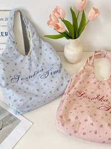 Floral print canvas tote bags in blue and pink with artistic lettering on white table