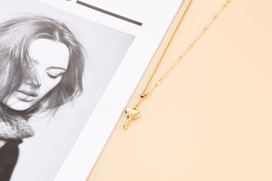 Close-up of golden stainless steel heart key pendant necklace on a warm background