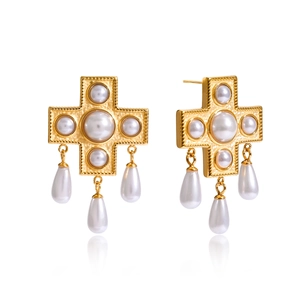 Dettaglio macro degli orecchini a croce placcati oro con eleganti perle finte