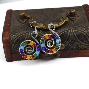 Detail view of handmade spiral wire-wrapped earrings with colorful natural crystal beads