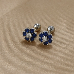 Detail of flower-shaped blue zircon earrings with secure screw back on gold fabric