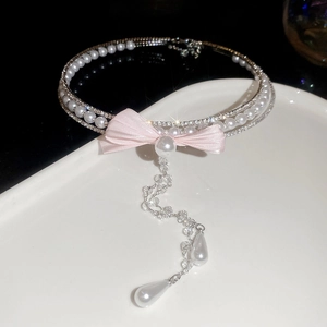 Detailed close-up of pearl and rhinestone bow necklace with elegant long fringe tassels