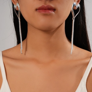 Detail view of silver heart-shaped zircon earrings with long rhinestone tassels on model