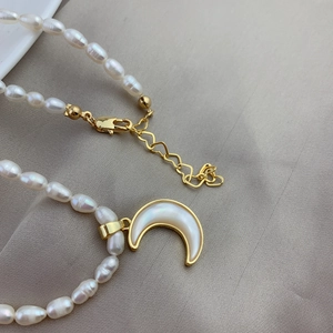 Detail of freshwater pearl necklace with mother of pearl moon pendant and heart clasp