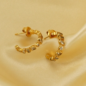 Detail showing gold U-shaped earrings with mixed-cut cubic zirconia on silk fabric