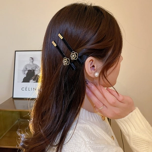 Elegant set of black hair clips featuring gold camellia flowers worn by a model