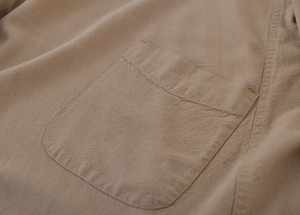 Detailed macro view of beige washed linen apron pocket with yellow reinforced stitching