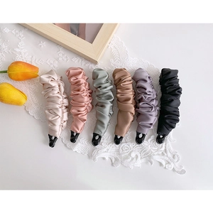 Flat lay view of six colorful pleated satin bow banana hair clips on white lace