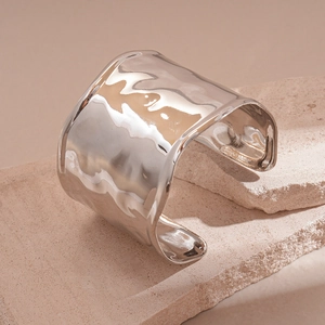 Detail of wide silver cuff bracelet with liquid metal texture on neutral stone base