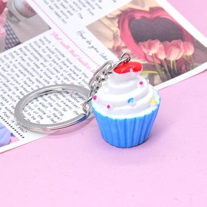 Close-up of cute 3D resin cupcake keychain with white cream and a tiny red heart