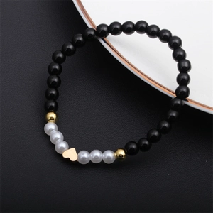 Detail of beaded bracelet with black agate beads, pearls, and golden heart charms
