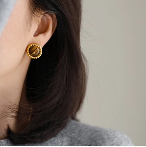 Close-up of retro golden twist earrings with brown tiger eye stone on female model