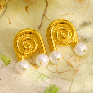 Golden spiral hoop earrings with white pearls on a vintage textured paper background
