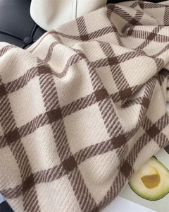 Close-up of beige and brown plaid scarf showing soft texture and cozy fabric weave