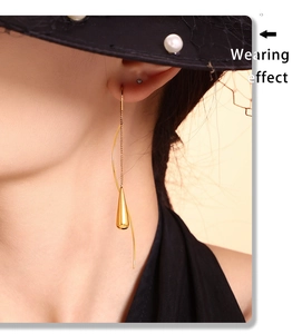 Elegant gold-tone tassel earrings featuring thin chains and teardrop pendants on a model
