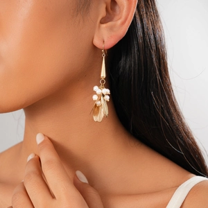 Detailed close-up of golden floral pearl earrings with petal tassels on model