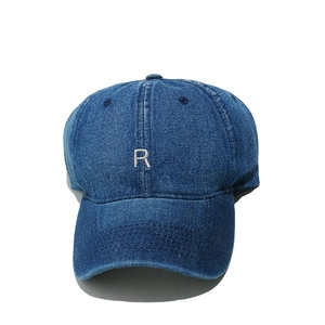 Macro detail of dark blue denim baseball cap featuring white embroidered R letter