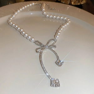 Gros plan du collier de perles avec un pendentif nœud argenté serti de diamants brillants