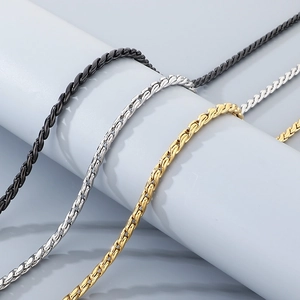Detail of snake chain necklaces in black, silver, and gold finish hanging on white decor