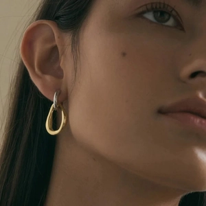 Close-up of model wearing two-tone gold and silver geometric drop earrings