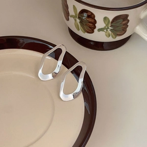 Detail view of abstract 925 sterling silver irregular earrings on a ceramic dish