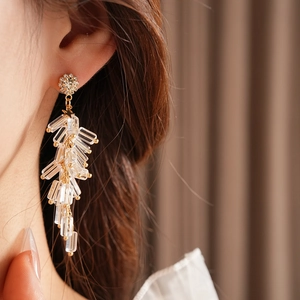 Close-up of gold-plated wheat spike earrings with sparkling crystals worn by a model