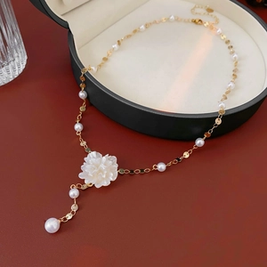 Detail of floral pearl necklace with gold sequins inside a black jewelry gift box
