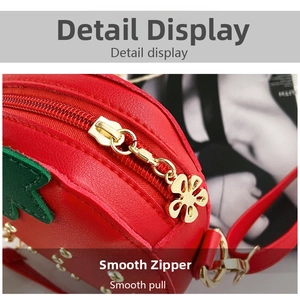 Detail of red strawberry crossbody bag featuring gold metal zipper and flower-shaped puller