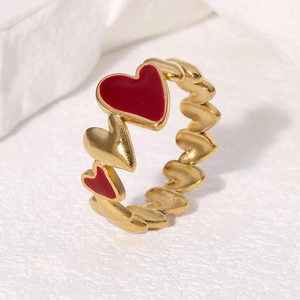 Close-up of gold-plated rings with red enamel hearts on a warm textured background