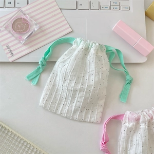 Detalle de bolsa de lunares con cordones rosa y verde menta en un escritorio limpio
